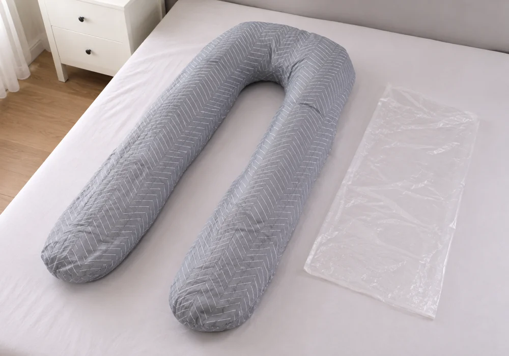 Pregnancy pillow freshly unpacked, still compressed and uneven, laid flat on a bed with its folded packaging beside it
