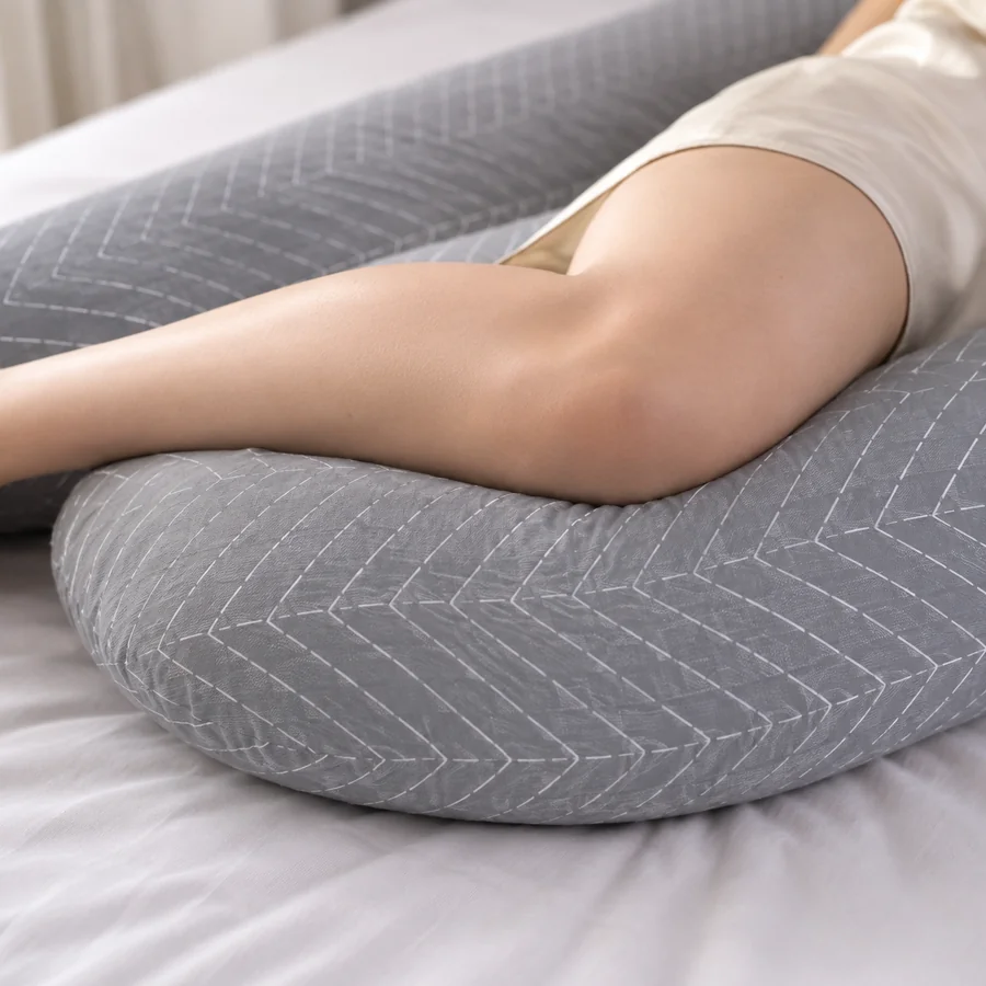 Detail of a bent knee resting on the pillow’s arm, the thigh held level